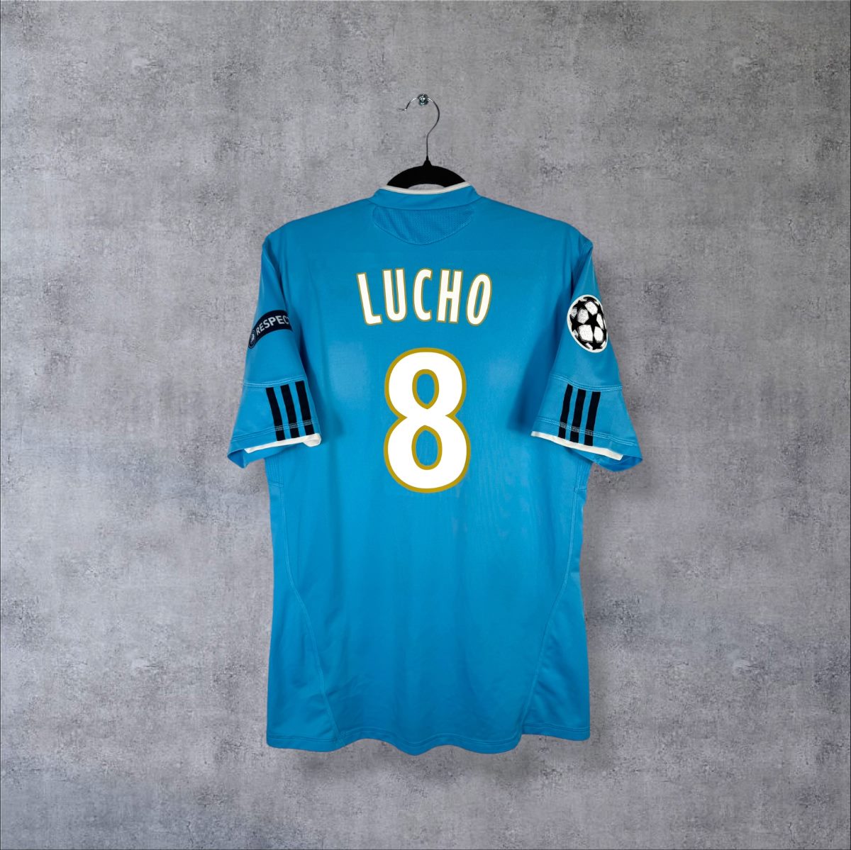 Maillot OM 2010-2011 extérieur adidas bleu ciel, dos floqué Lucho 8, badges Ligue des champions et Respect