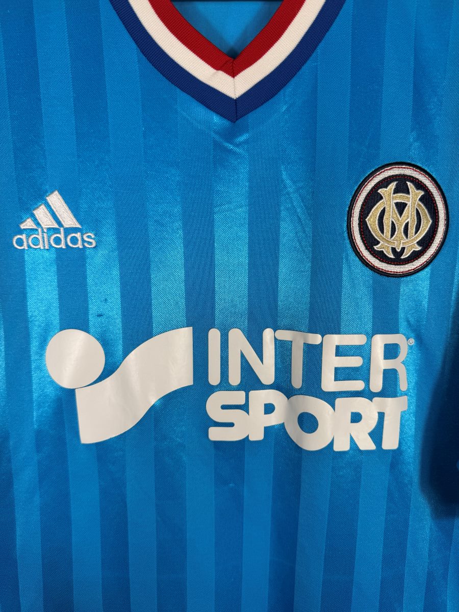 Détail de l'écusson OM brodé doré et du sponsor Intersport sur le maillot extérieur 2012-2013