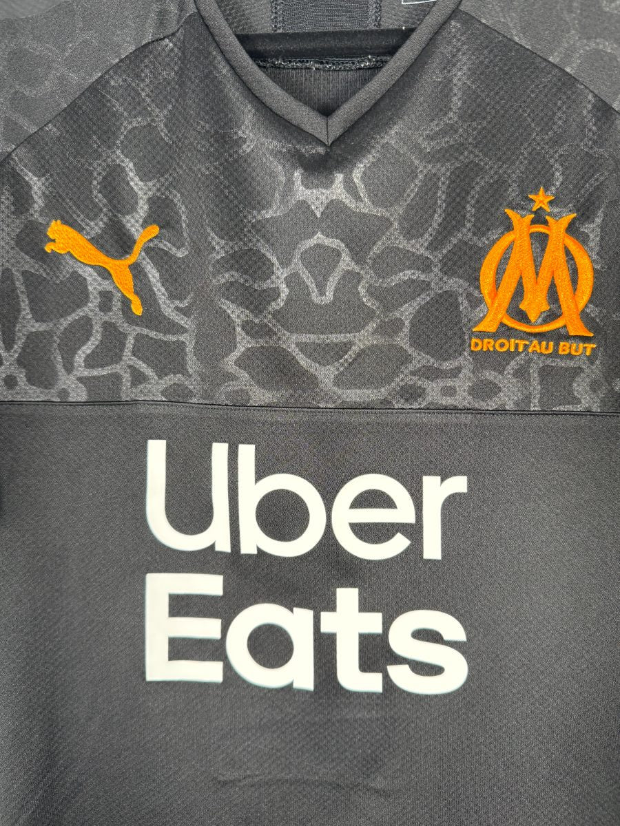 Détail de l'écusson OM brodé orange Droit au But et du motif texturé du maillot third 2019-2020