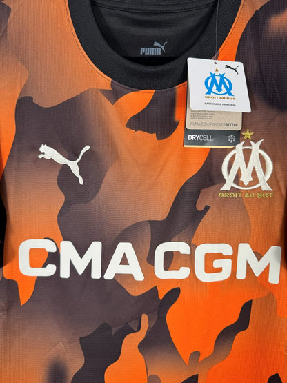 Détail de l'écusson OM brodé doré Droit au But et du sponsor CMA CGM sur le maillot third 2023-2024