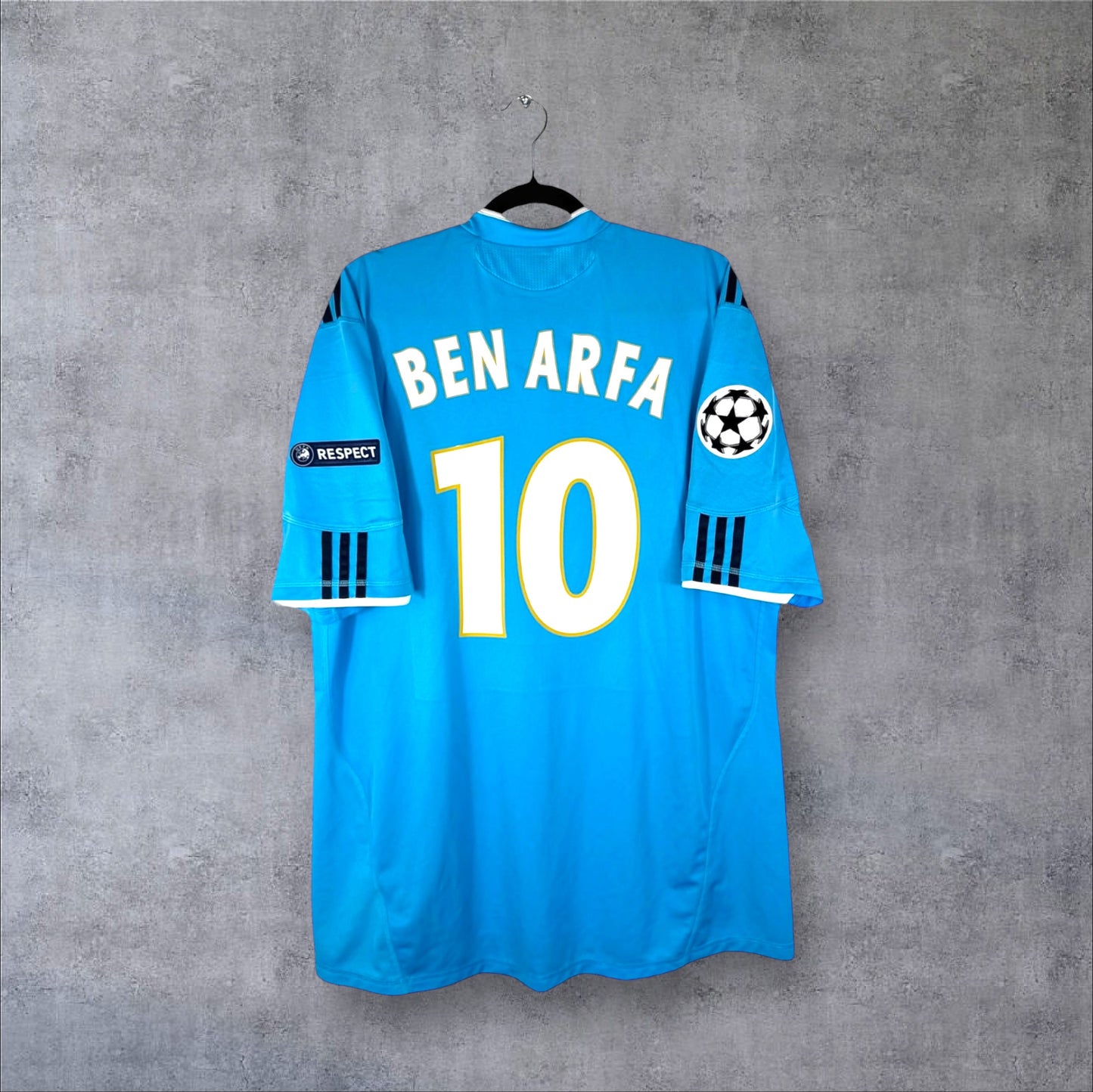 Dos du maillot OM Extérieur 2010/11 bleu à carreaux avec flocage BEN ARFA 10 et patchs UCL.