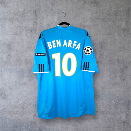 Dos du maillot OM Extérieur 2010/11 bleu à carreaux avec flocage BEN ARFA 10 et patchs UCL.