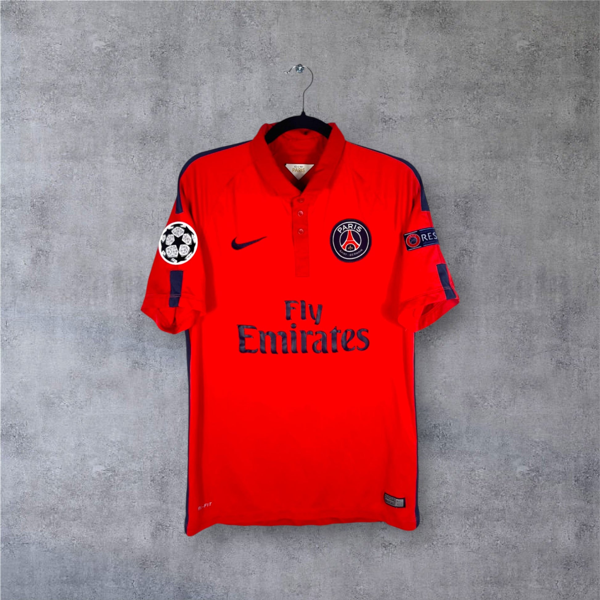 Vue de face du maillot PSG Third rouge avec col polo et patchs Ligue des Champions.