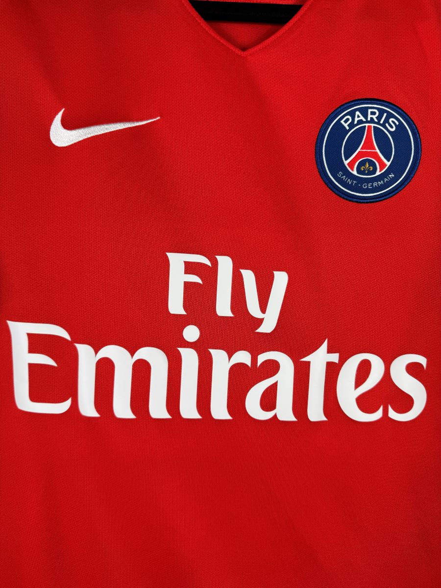 Détail de l'écusson brodé du Paris Saint-Germain et du swoosh Nike sur le maillot extérieur rouge 2016-2017