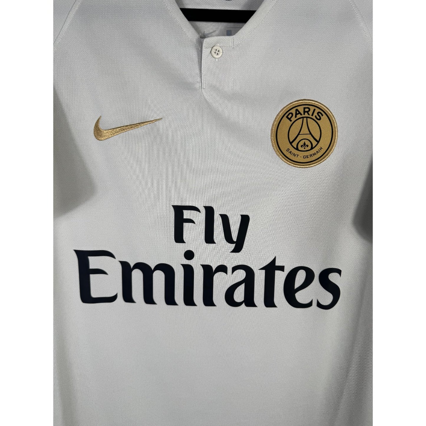 Détail de l'écusson doré du Paris Saint-Germain et du logo Nike