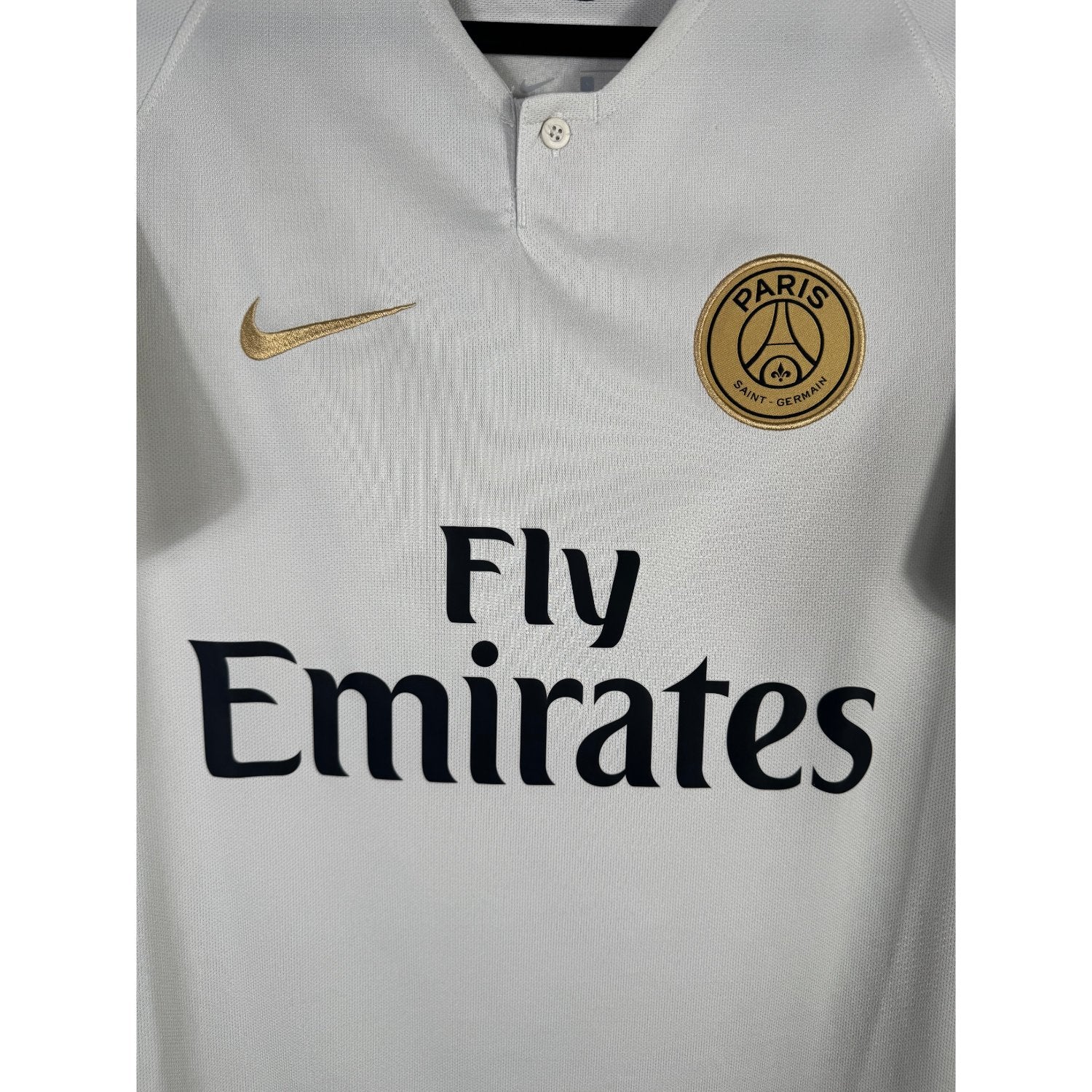 Détail de l'écusson doré du Paris Saint-Germain et du logo Nike
