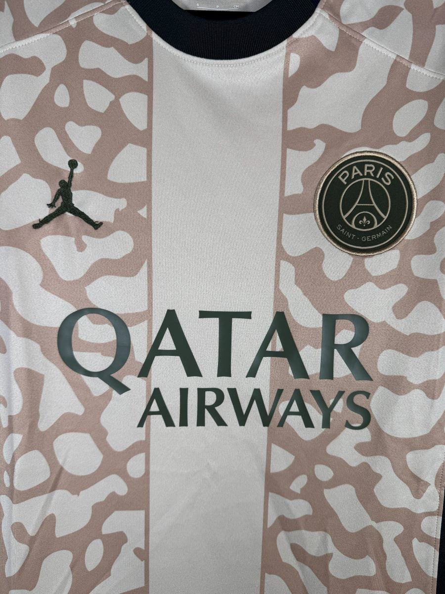 Détail de l'écusson PSG doré et du logo Jumpman sur le maillot fourth 2023-2024