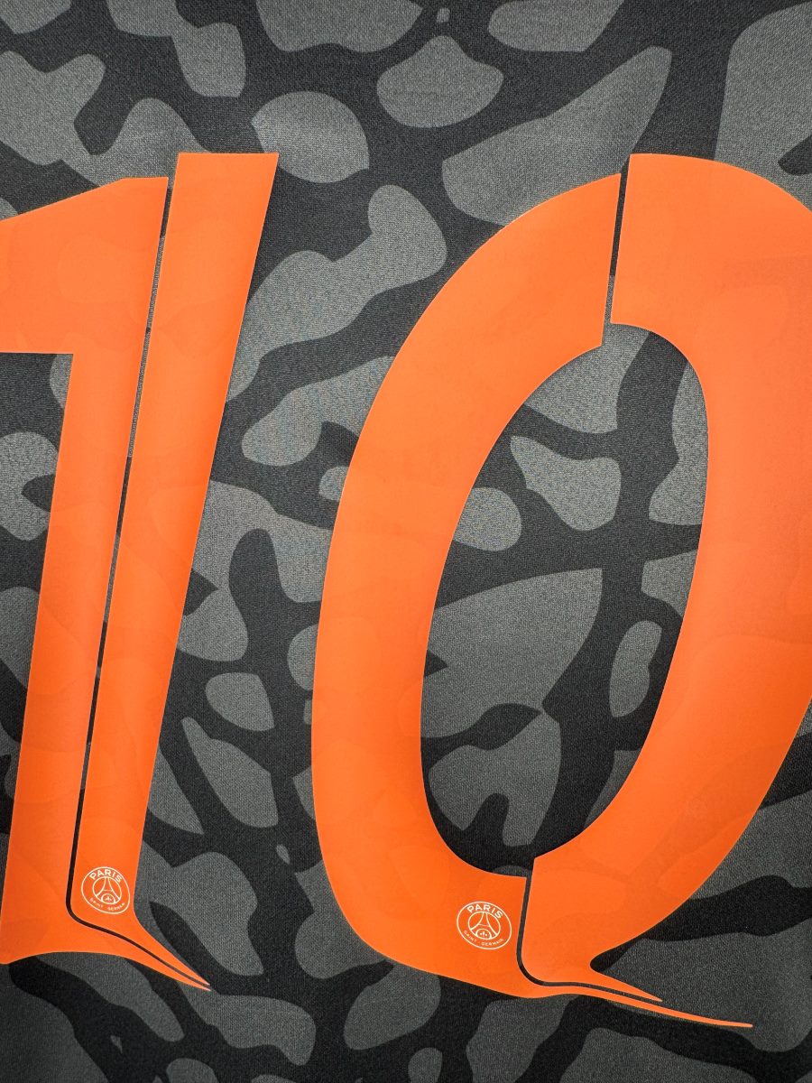 Détail du numéro 10 orange avec logo PSG, maillot third 2023-2024 Dembélé