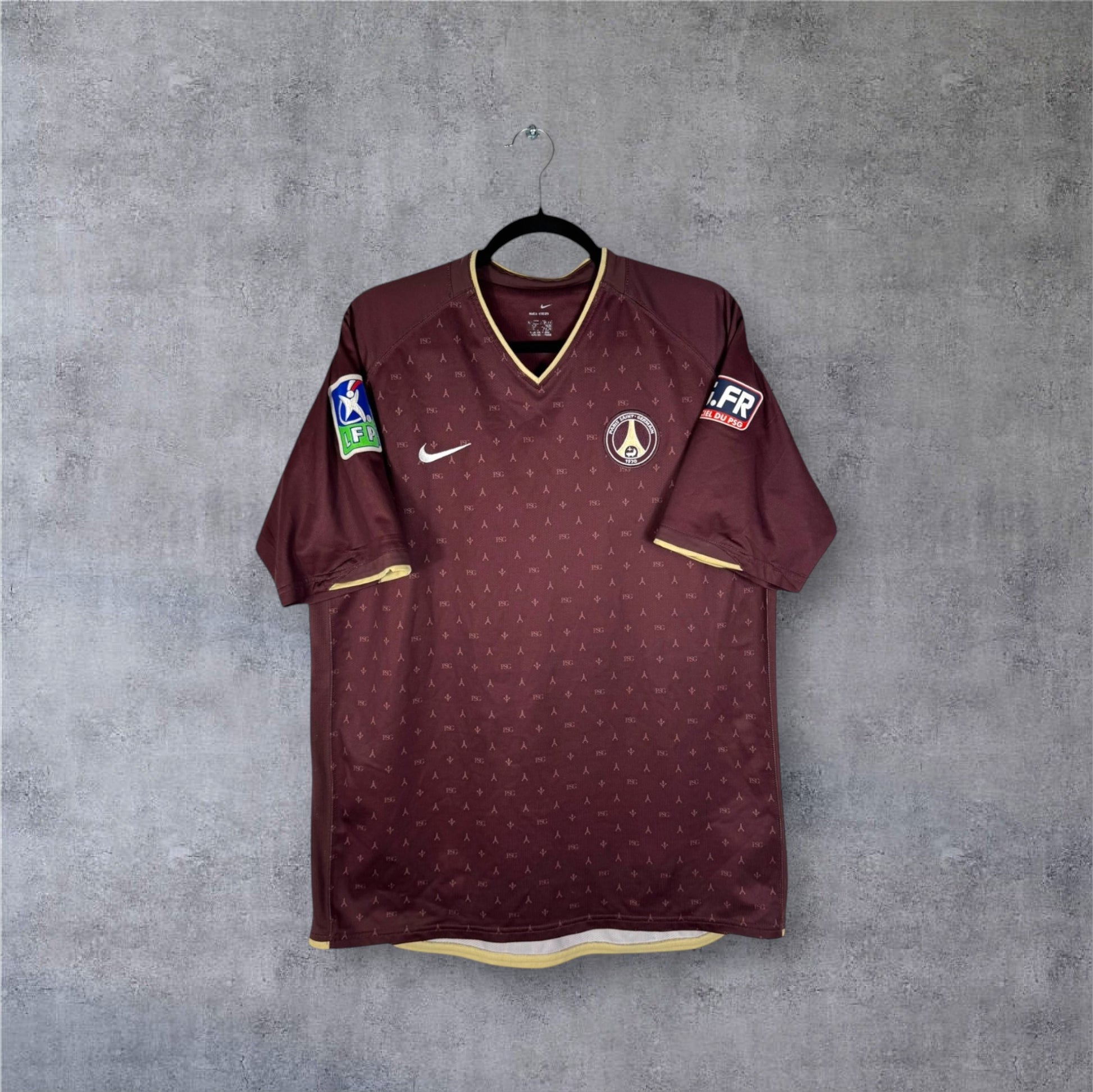Vue de face du maillot PSG Extérieur 2006/07 couleur chocolat/bordeaux avec motifs monogrammes dorés.
