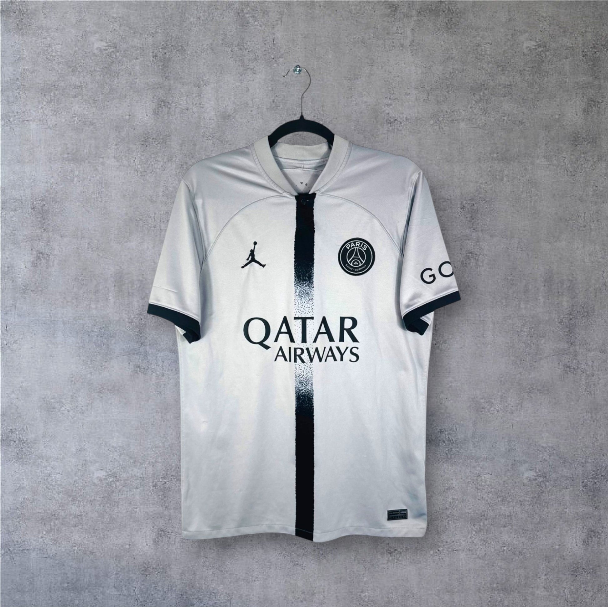 Vue de face du maillot gris PSG Jordan 2022/23 avec bande centrale noire fondue.