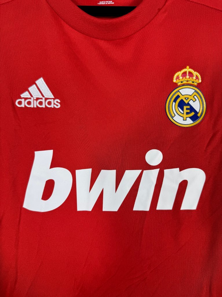 Détail de l'écusson du Real Madrid et du logo Adidas sur le maillot rouge