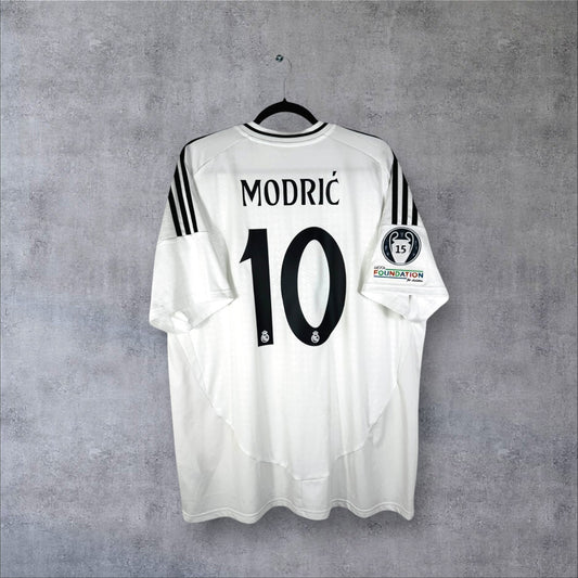 Dos du maillot Real Madrid Domicile 2024/25 blanc avec flocage noir MODRIĆ 10 et patchs UCL.