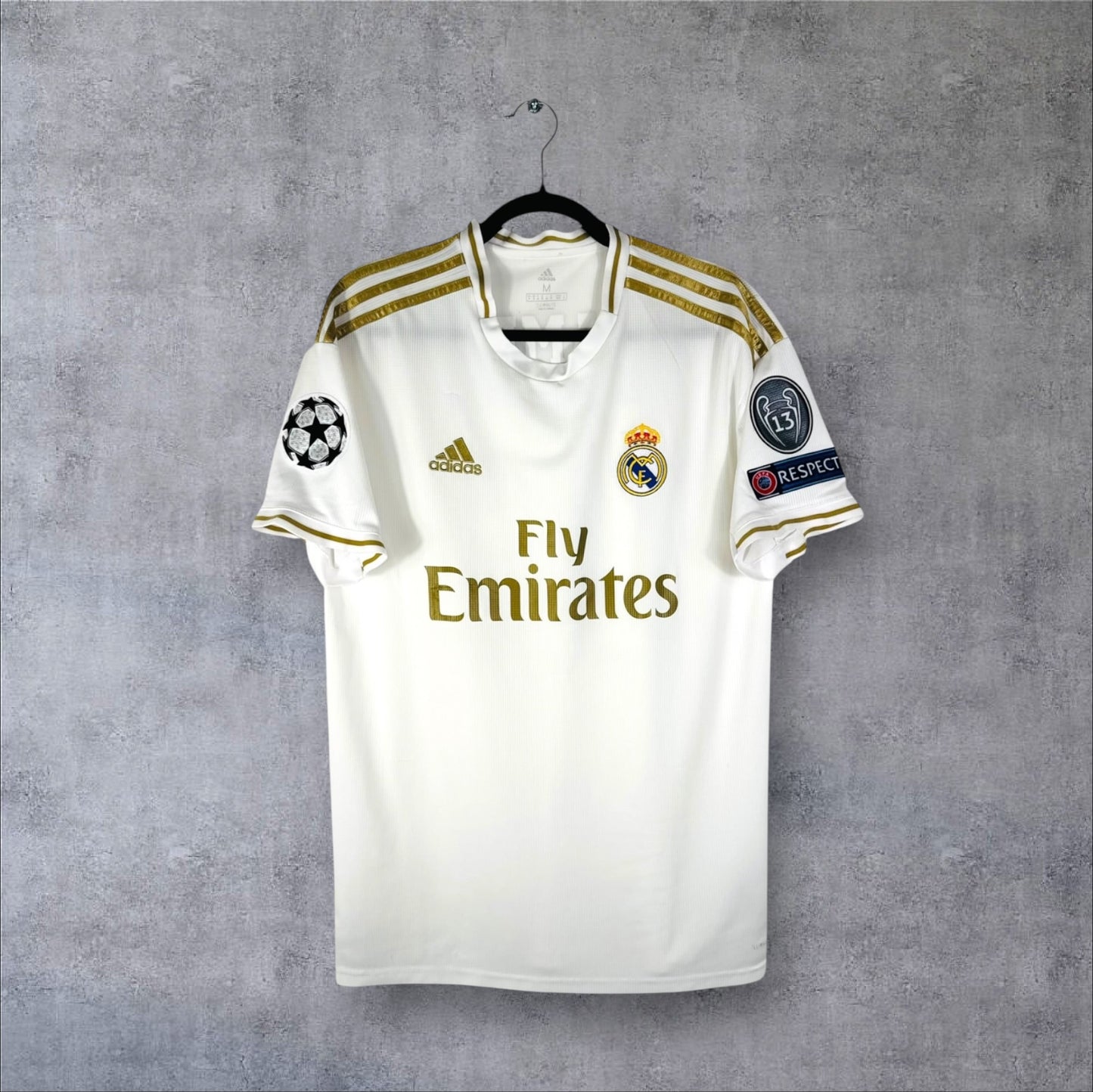 Vue de face du maillot Real Madrid Domicile 2019/20 blanc avec détails dorés et sponsor Fly Emirates.