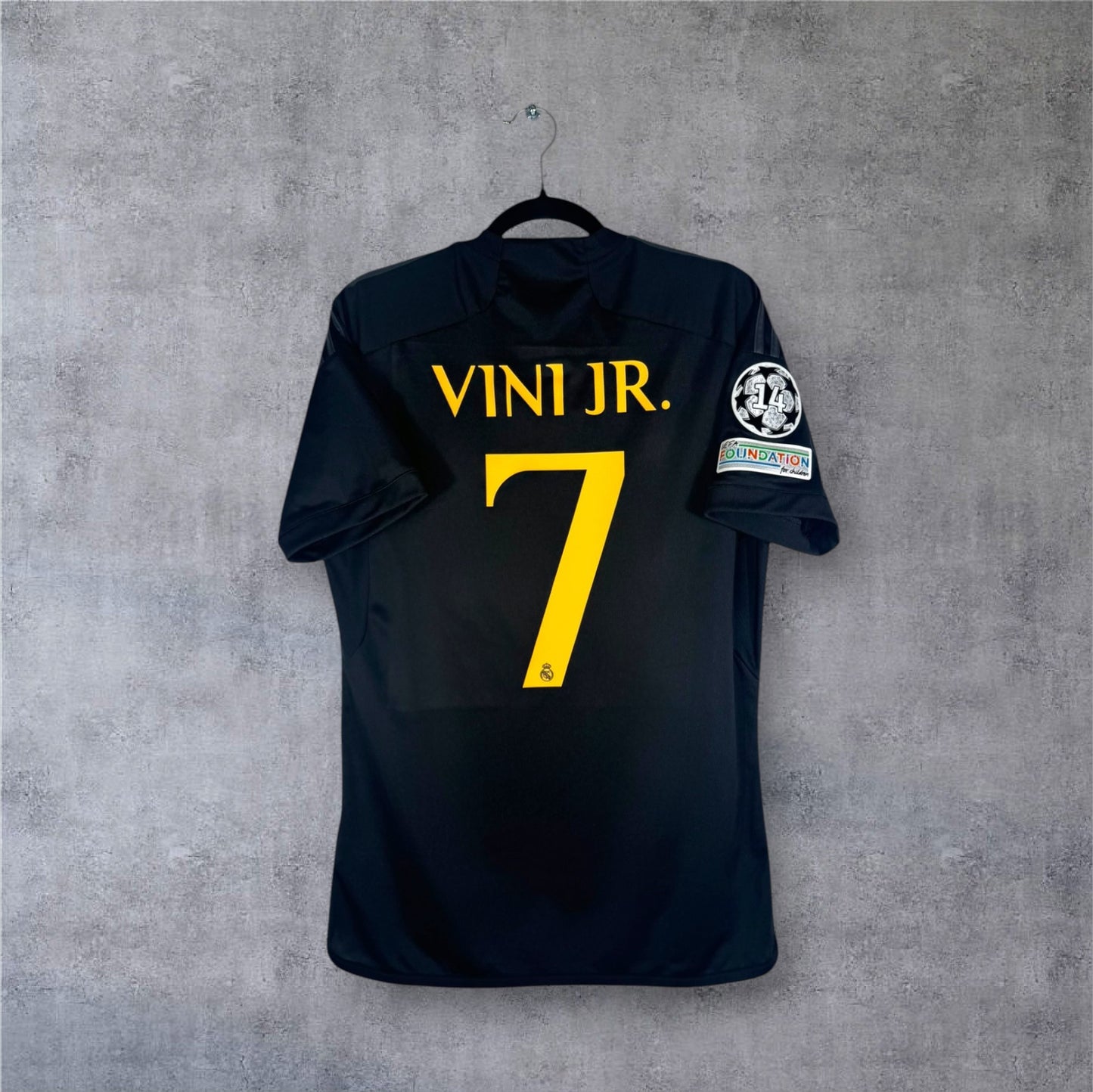 Dos du maillot Real Madrid noir avec flocage jaune VINI JR. 7 et patchs LDC.