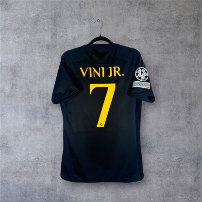Dos du maillot Real Madrid noir avec flocage jaune VINI JR. 7 et patchs LDC.