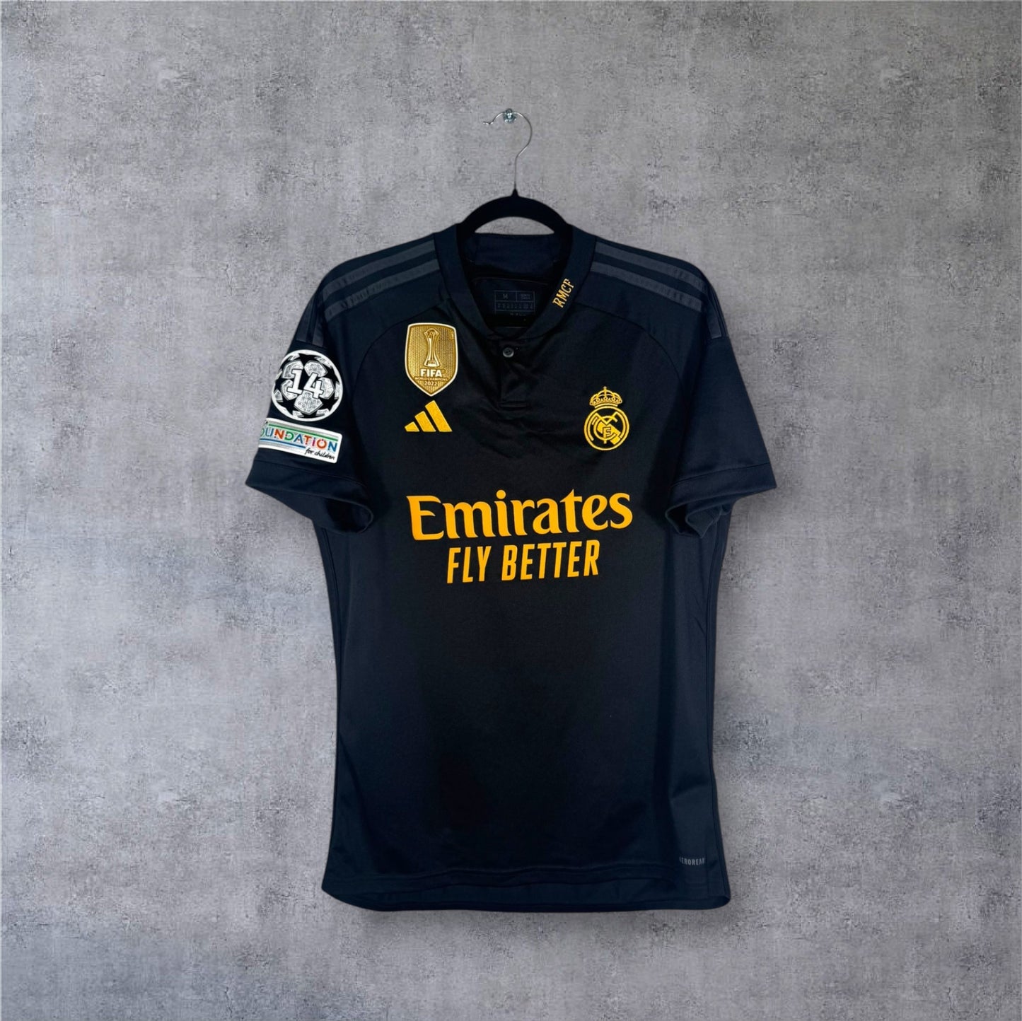 Vue de face du maillot Real Madrid Third 2024 noir avec badge FIFA doré au centre.