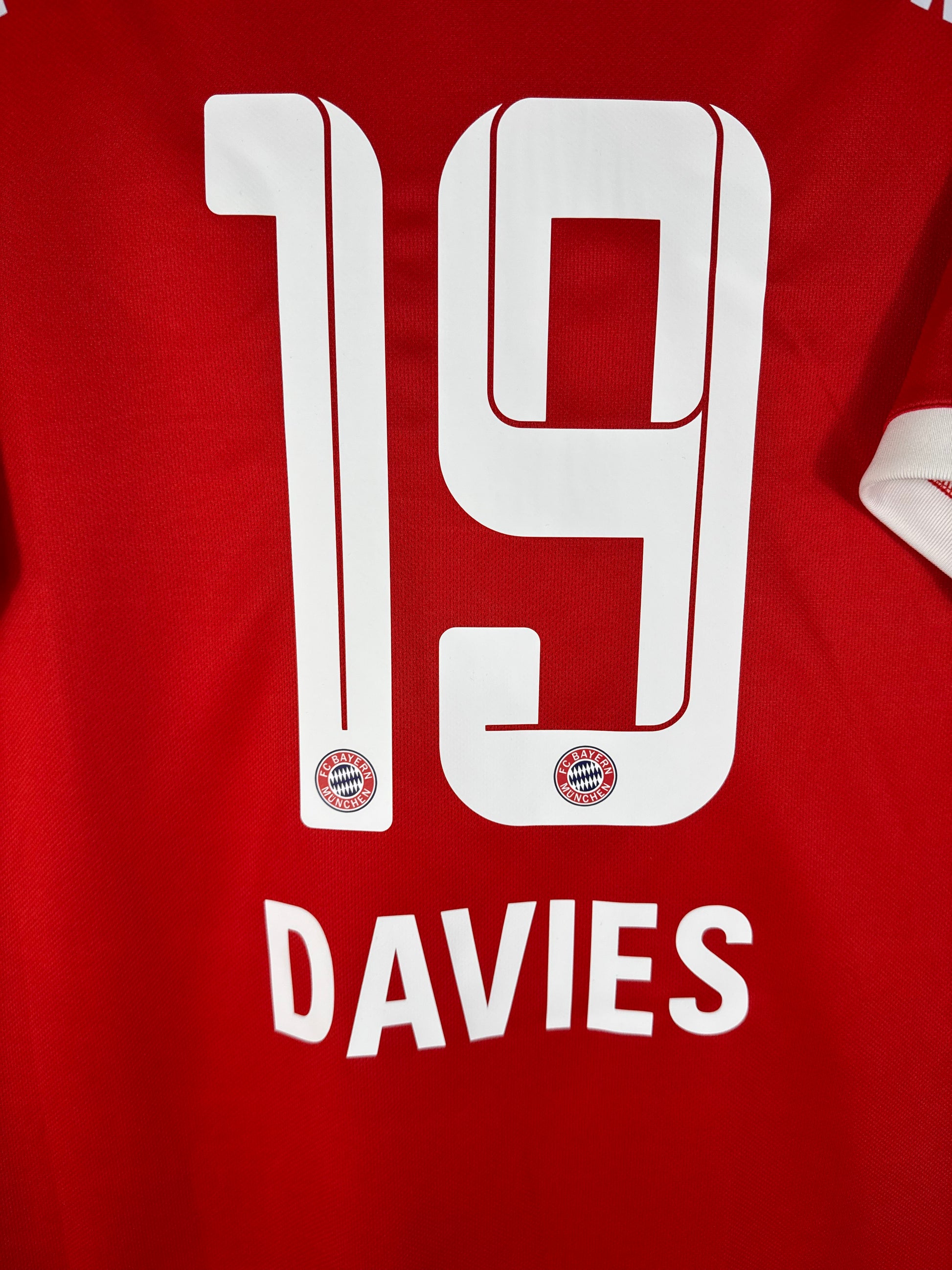 Zoom sur le numéro 19 blanc d'Alphonso Davies avec logo du club et typographie officielle Ligue des Champions.