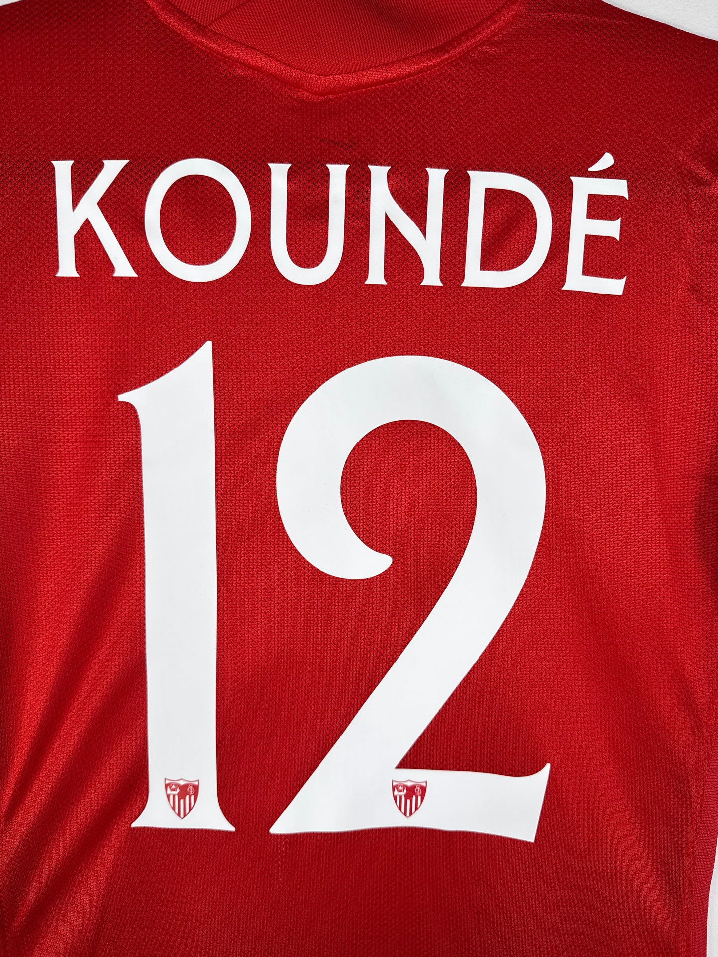 Zoom sur le nom KOUNDÉ et le numéro 12 blanc avec logo du club, typographie officielle Sevilla FC 2021-2022.