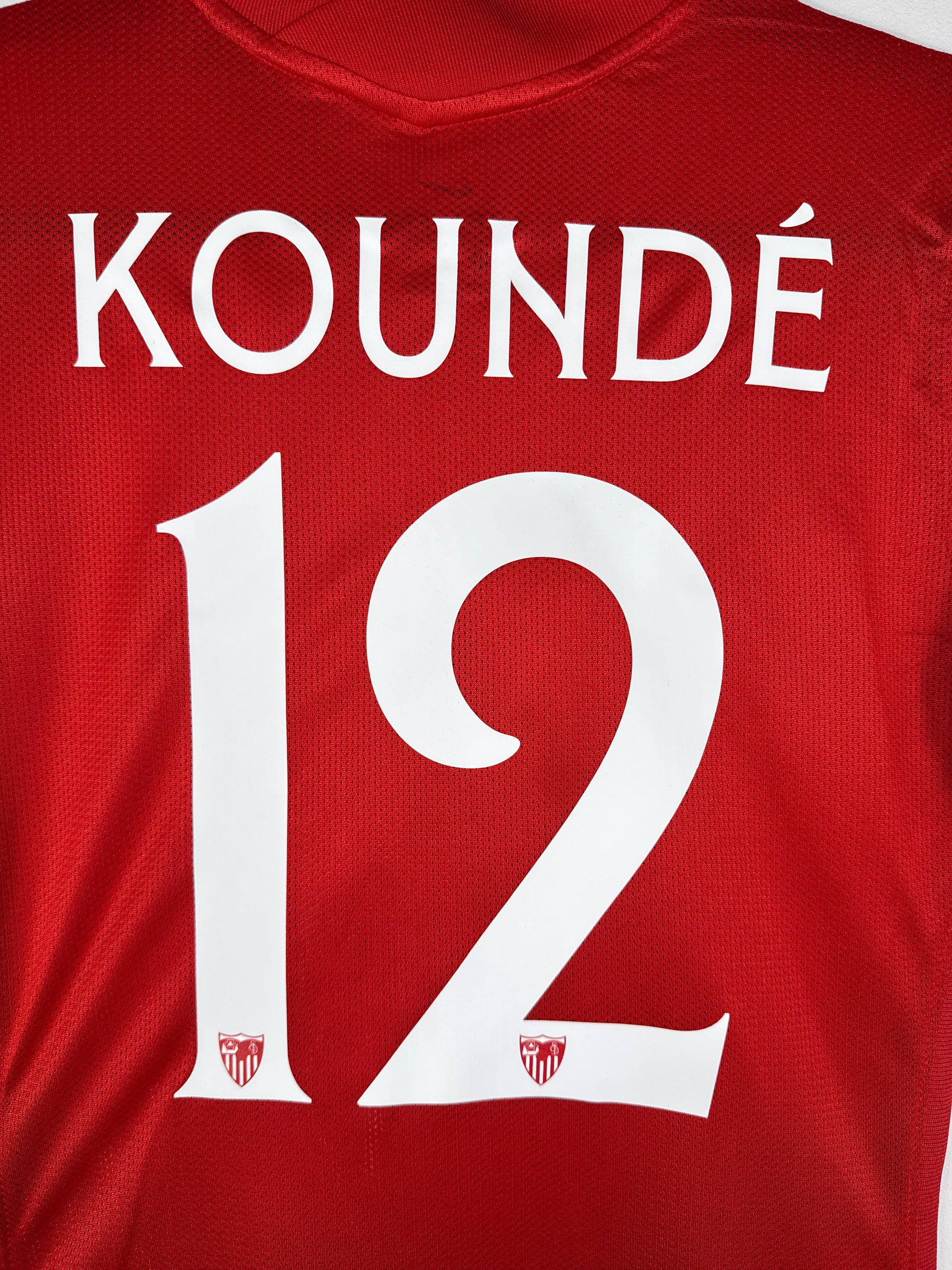 Zoom sur le nom KOUNDÉ et le numéro 12 blanc avec logo du club, typographie officielle Sevilla FC 2021-2022.