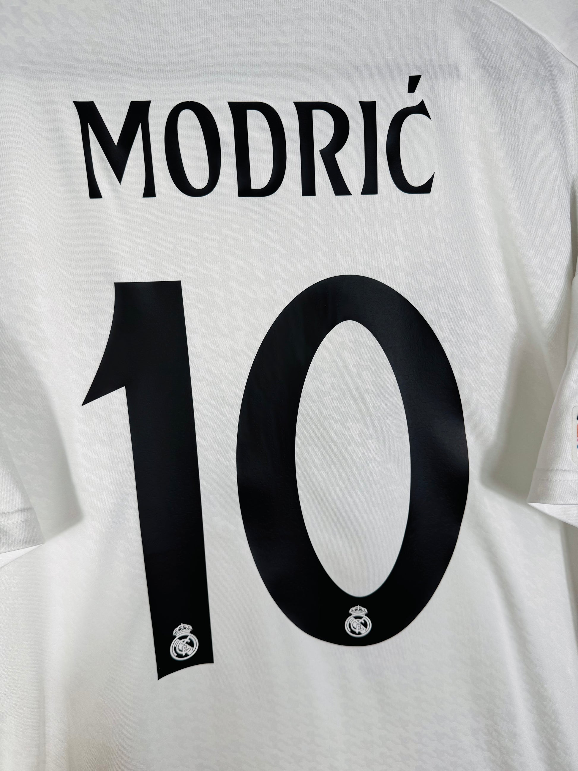 Zoom sur le nom MODRIĆ et le numéro 10 noir avec logo du club, typographie officielle UCL 2024-2025.